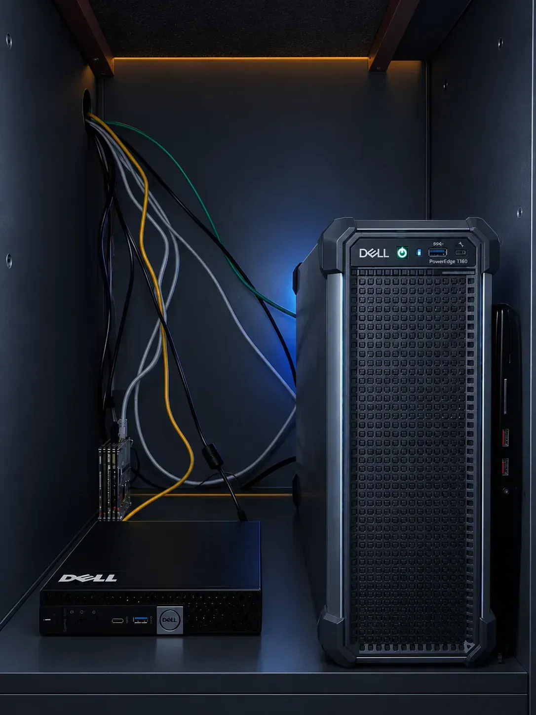 A Raspberry Pi, a Dell Micro PC, a Dell tower and a laptop inside a cabinet at home